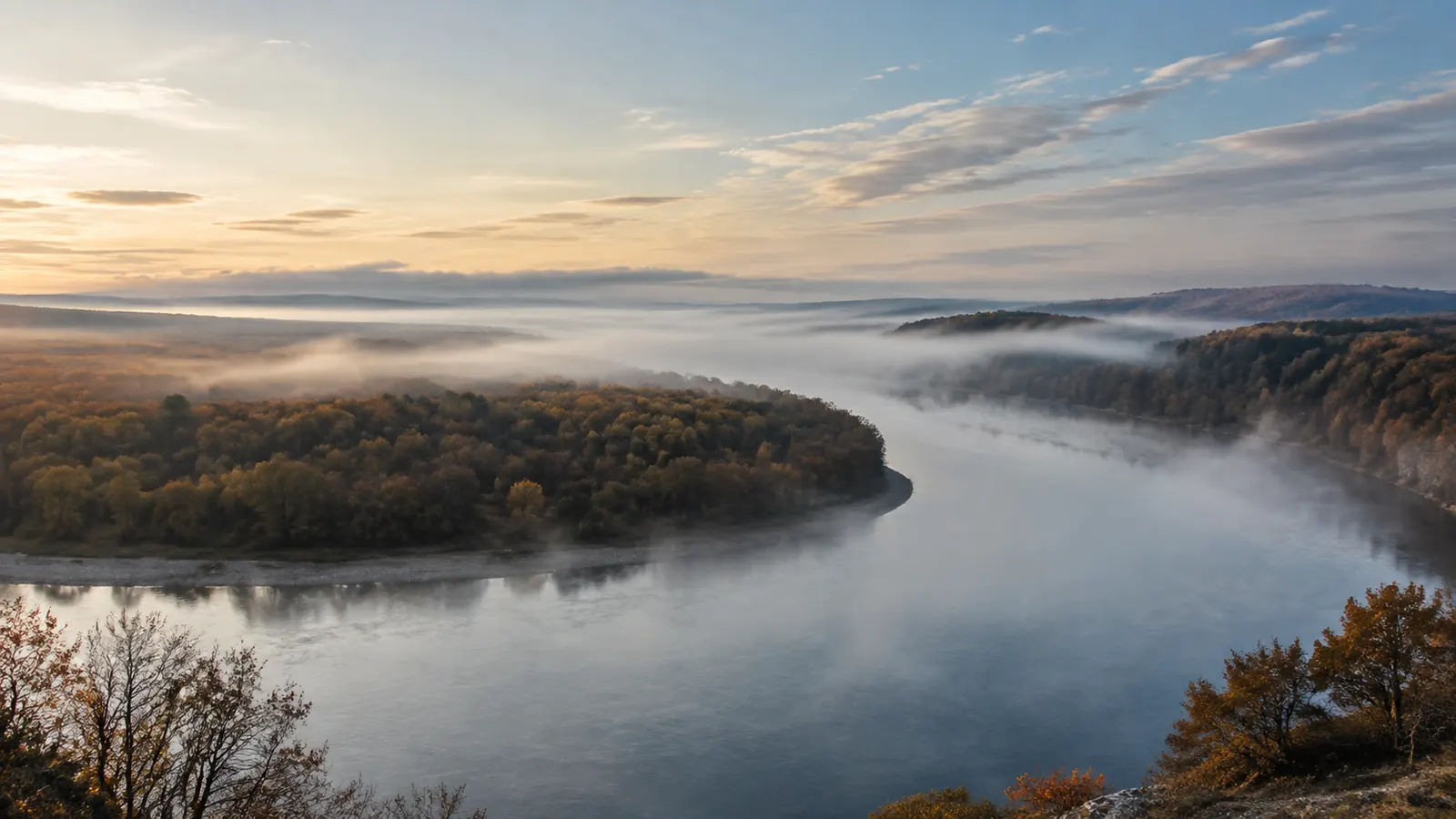 A river bends through a wide valley with low morning fog.
